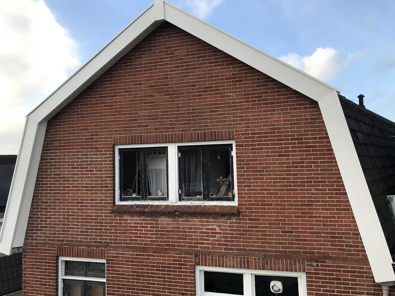 Vernieuwde witte boeidelen aan een bakstenen woning